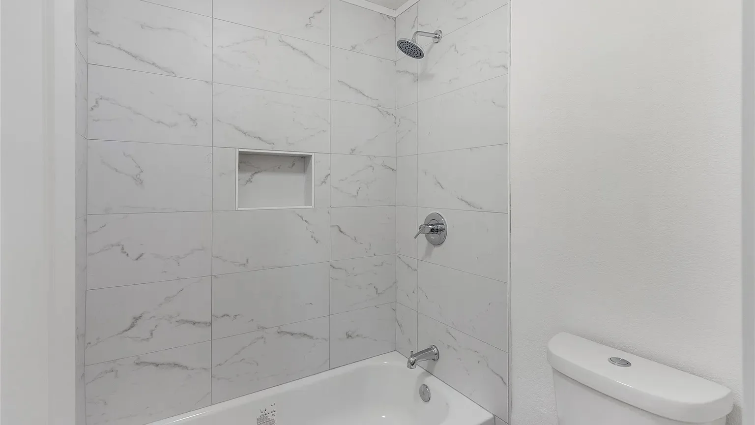Completed Lantern bathroom remodel with a marble tile tub surround and clean modern fixtures