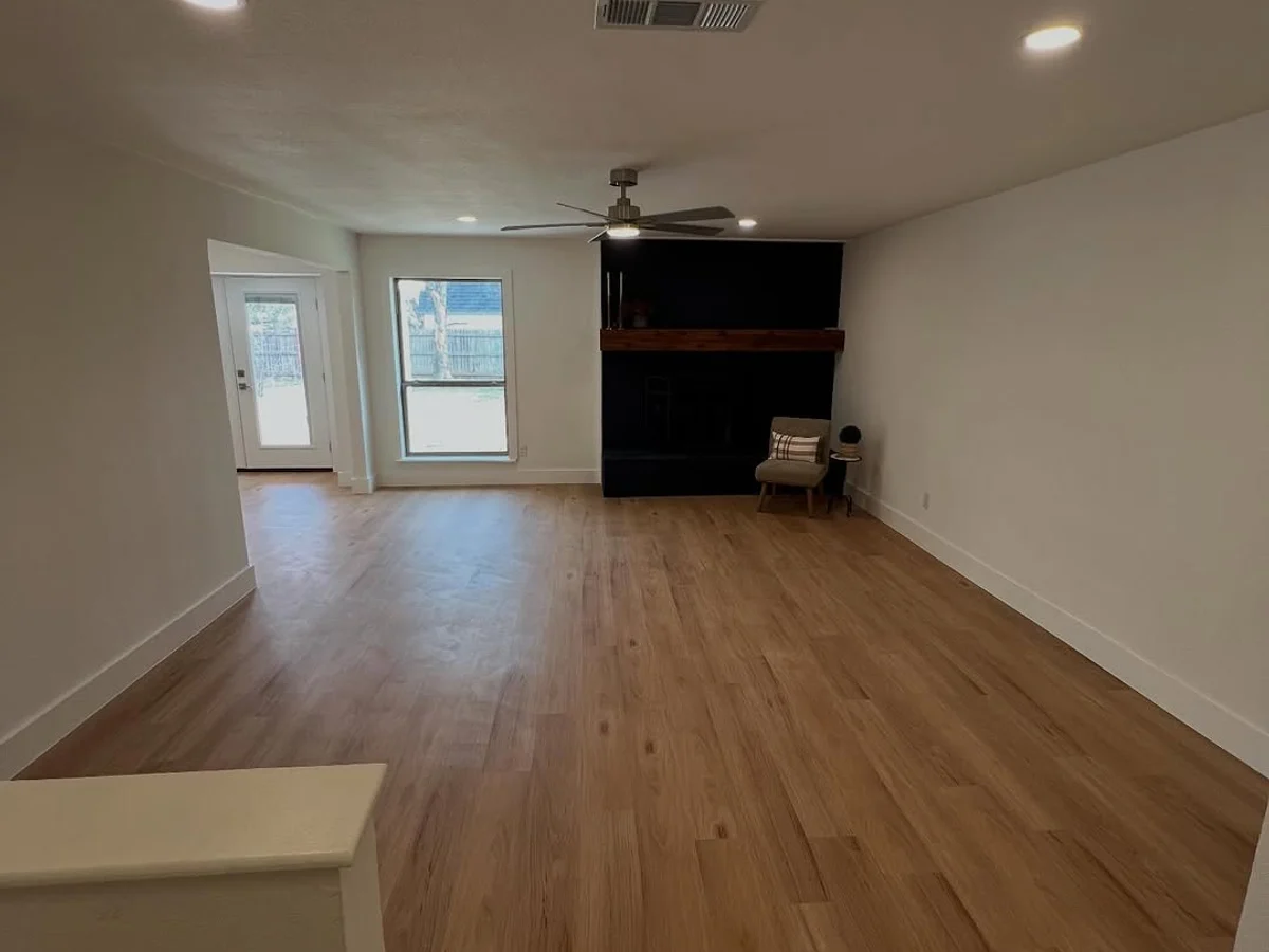 Living room with newly laid plank flooring running through to the kitchen