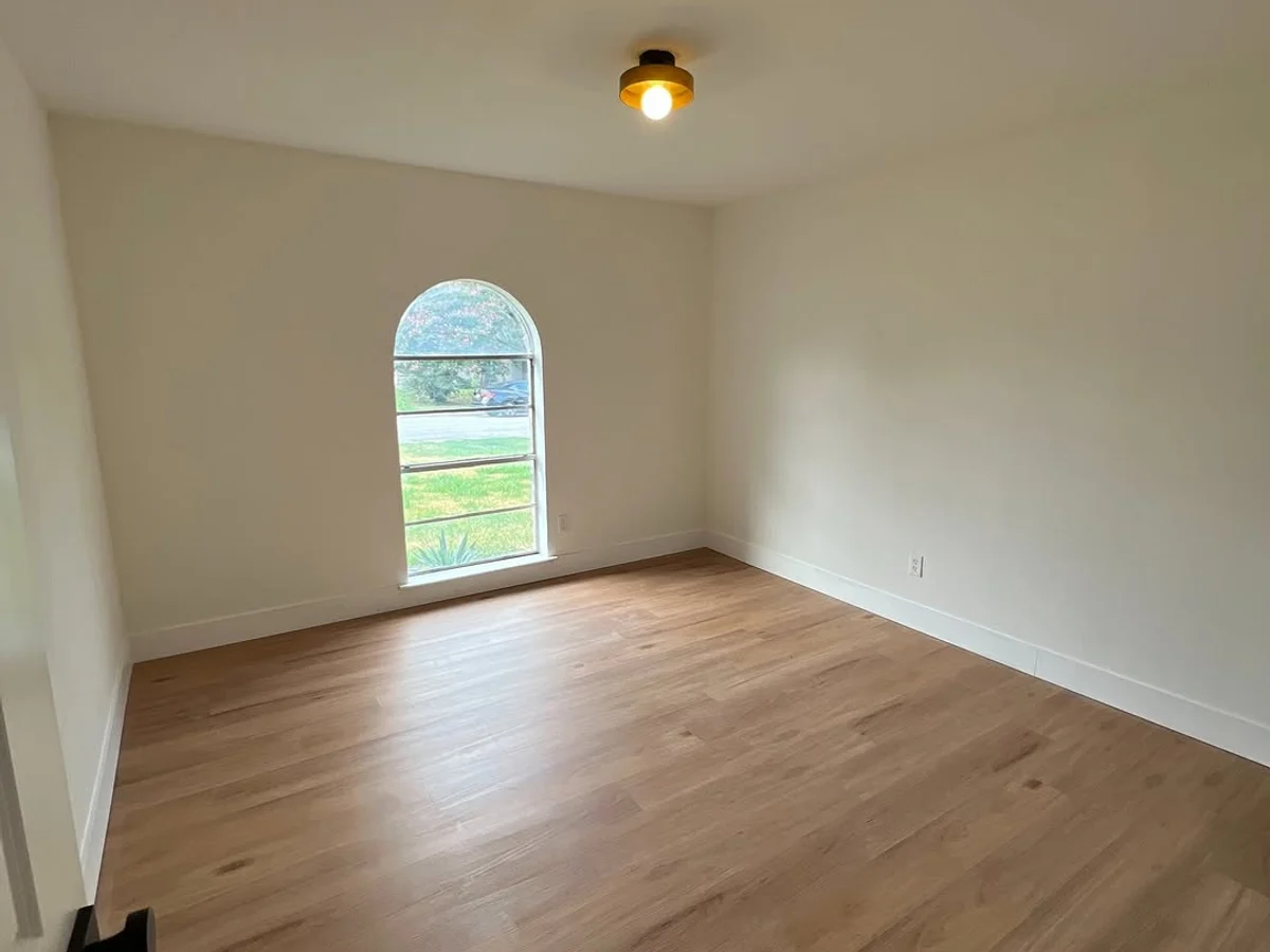 Repainted room with clean white walls, crisp trim, and an arched window