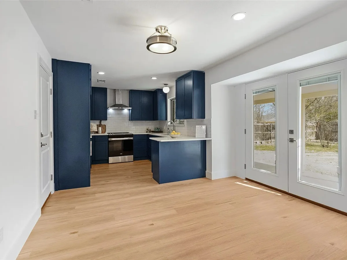 Completed kitchen remodel with navy cabinetry, oak flooring, and an open sightline to the entry