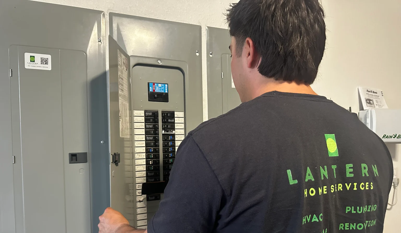 Daryl of Lantern Home Services inspecting a labeled residential electrical panel with a Lantern service sticker on the panel door